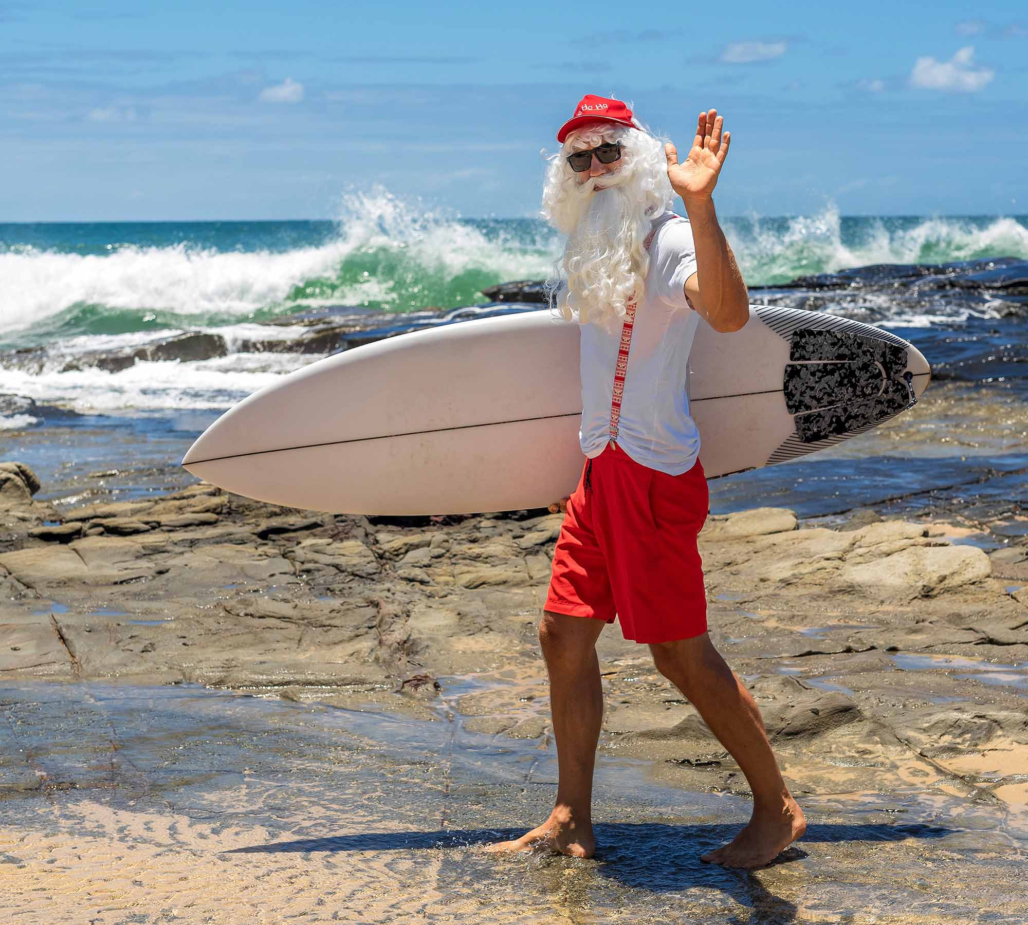 Santa Claus holds gift boxes with the ocean on backgraund